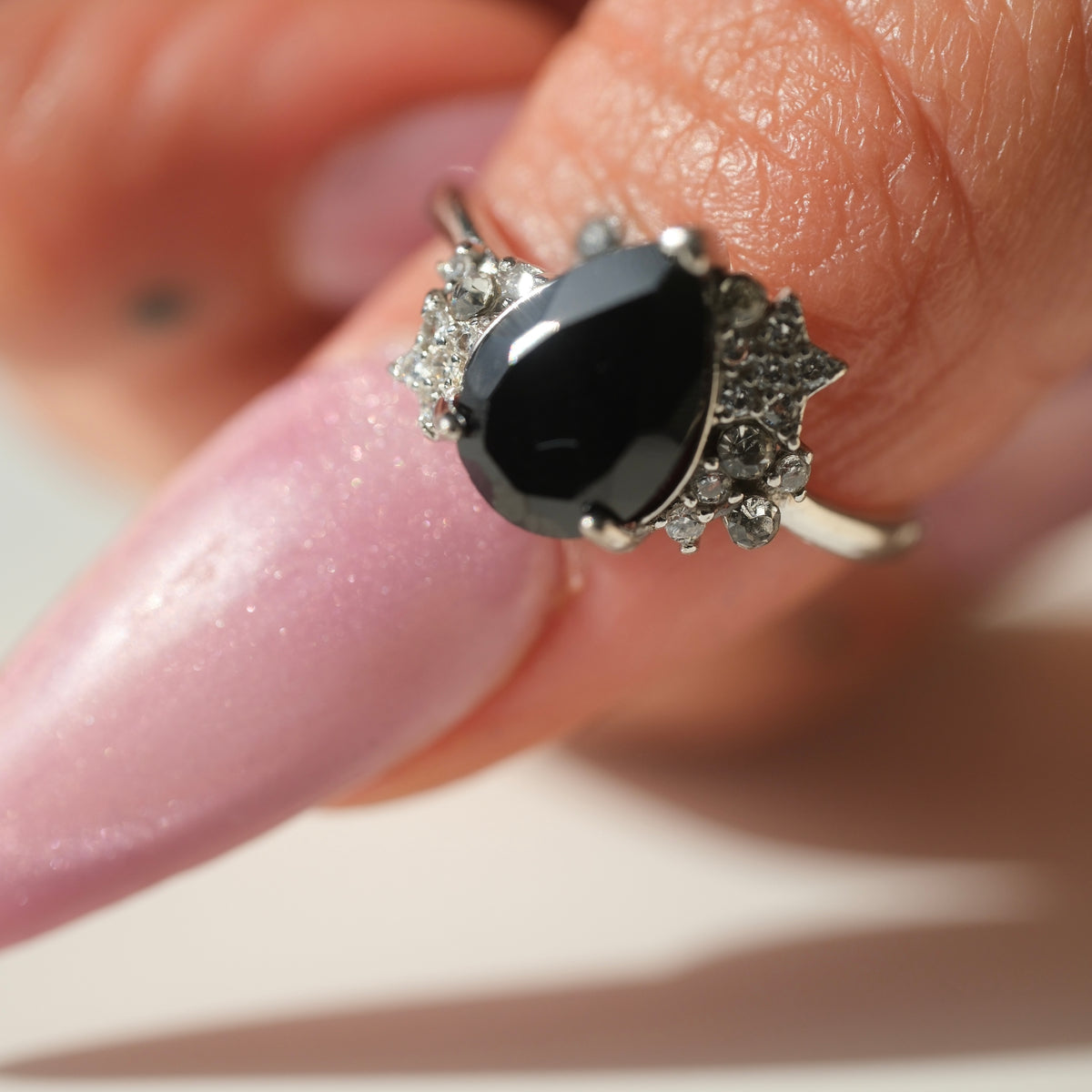 Black Spinel teardrop S925 adjustable ring with clear stone and star accents, shown on a finger