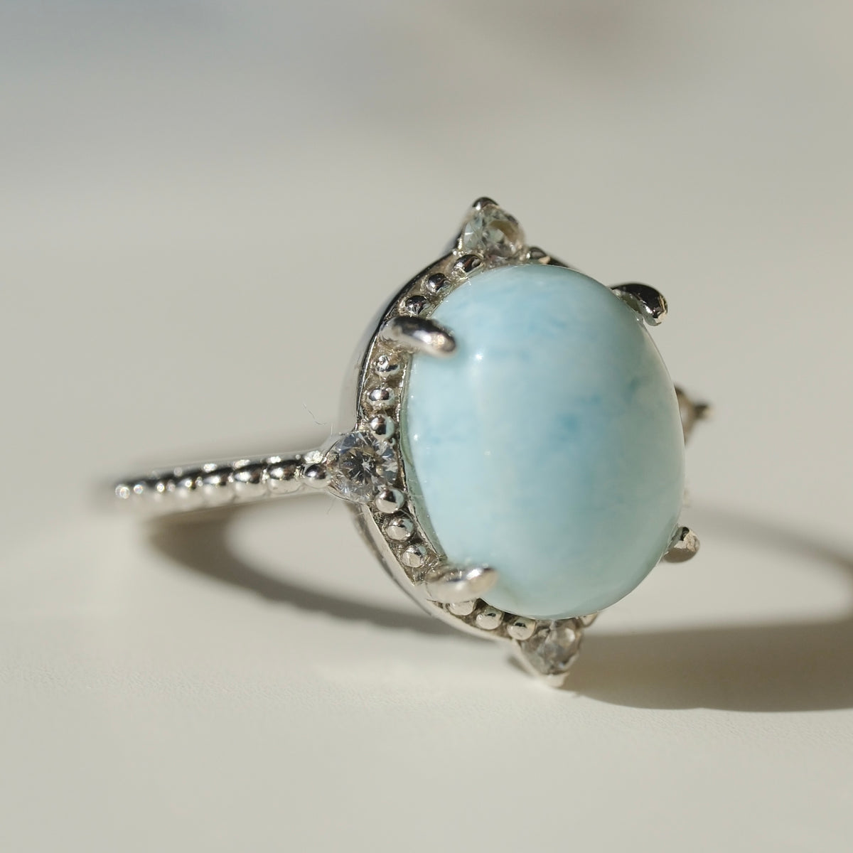 Larimar S925 adjustable ring with an oval pale blue stone, decorative silver border and clear accents