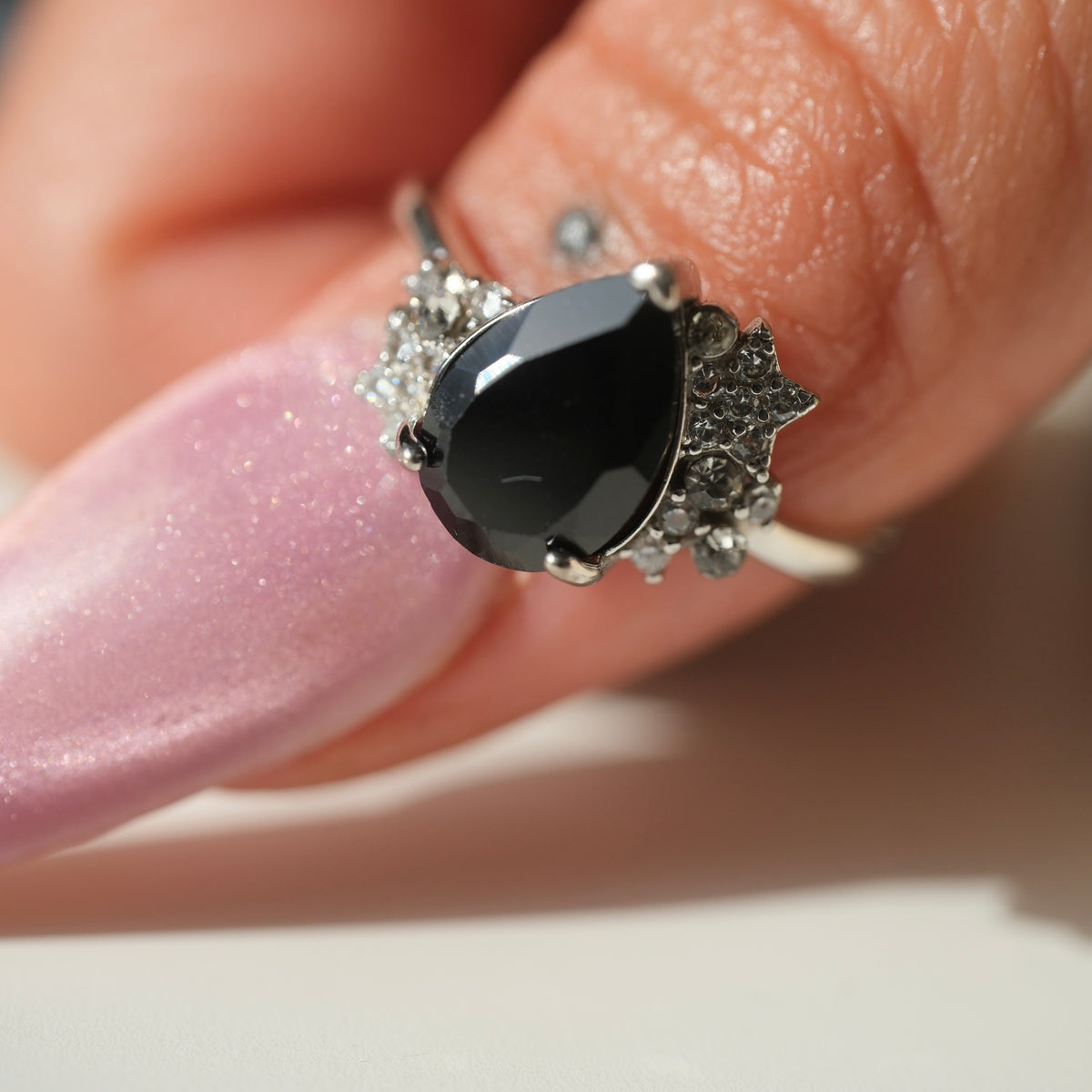 Black Spinel teardrop S925 adjustable ring with clear stone and star accents, shown on a finger