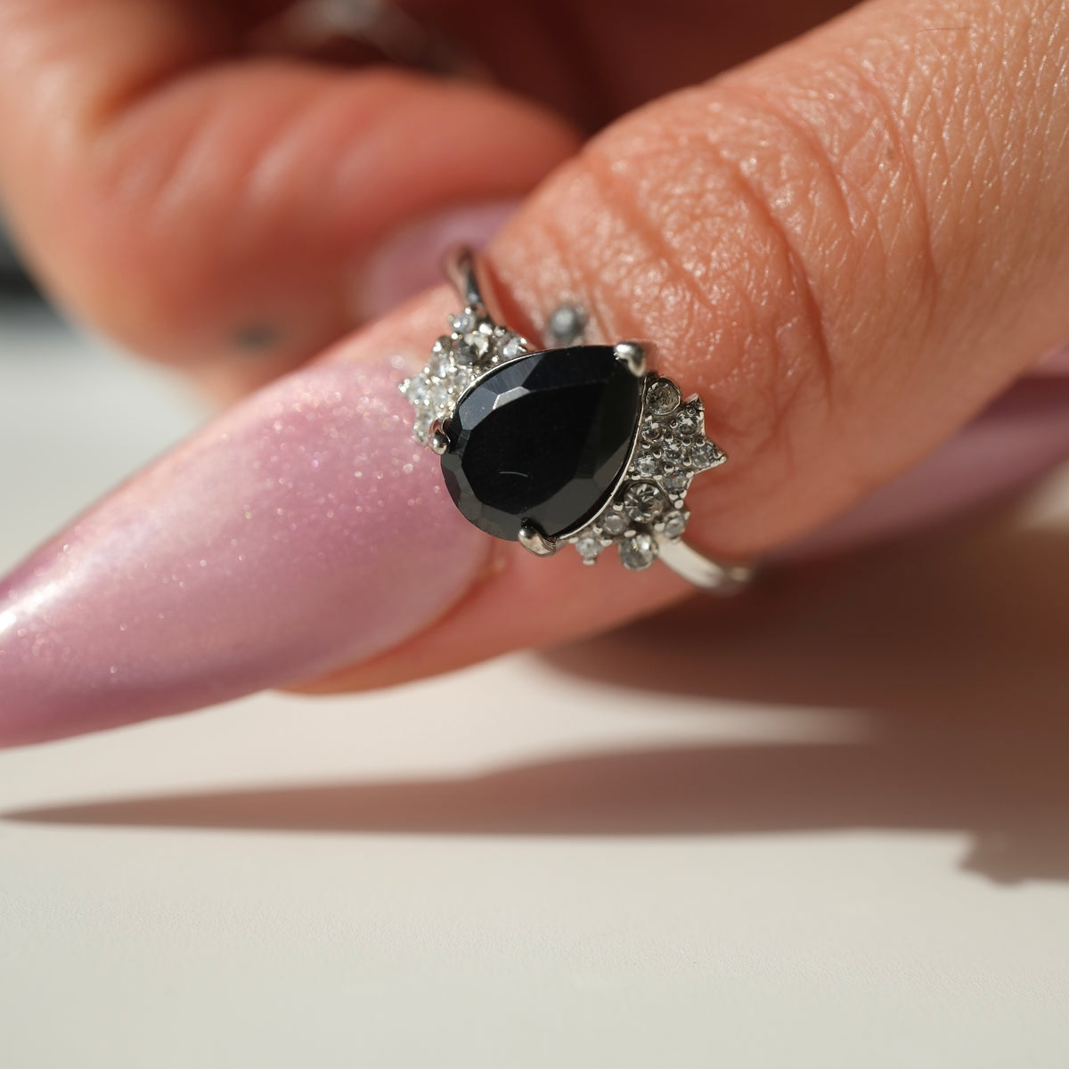 Black Spinel teardrop S925 adjustable ring with clear stone and star accents, shown on a finger