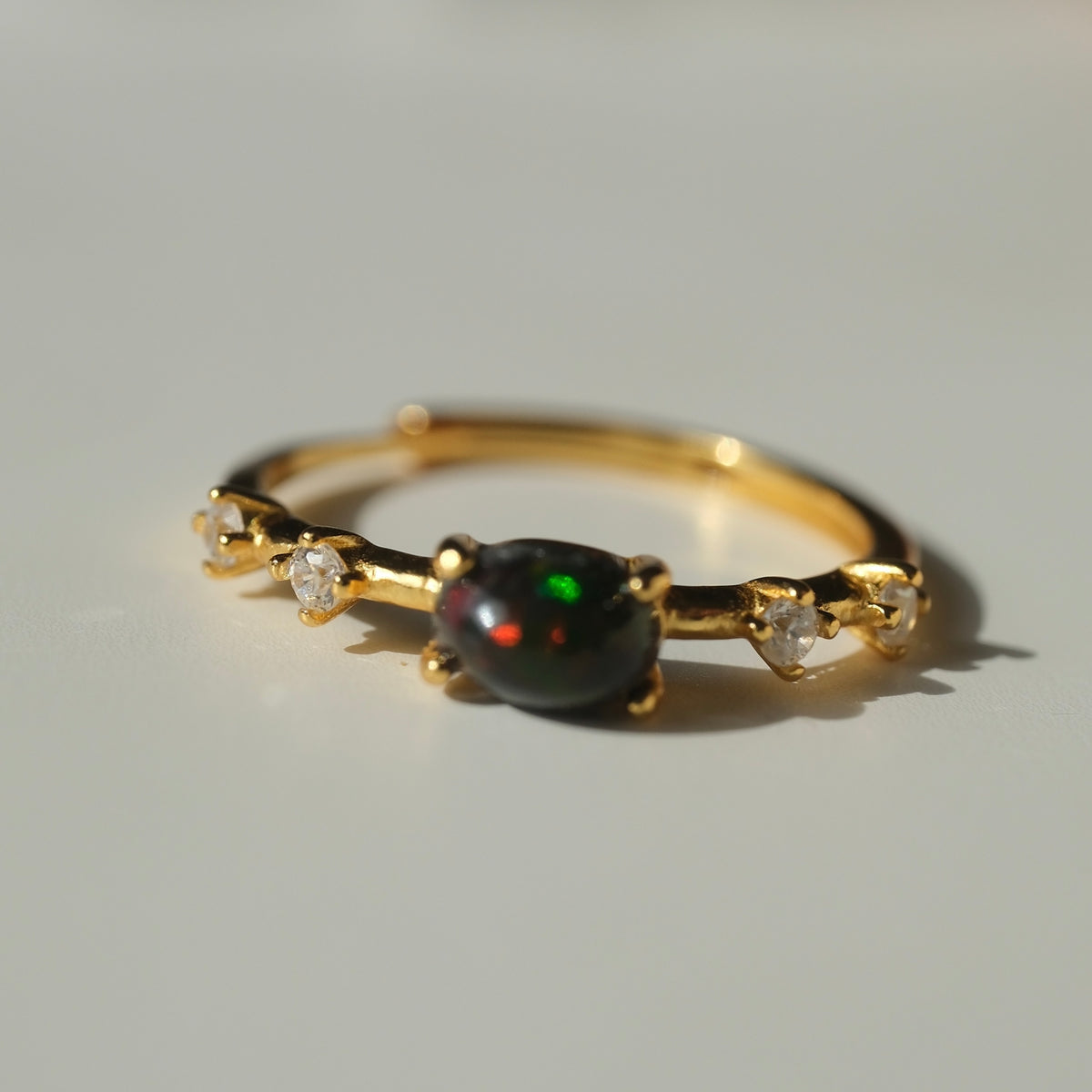 Ethiopian Black Opal adjustable ring with a gold-coloured band and clear accents