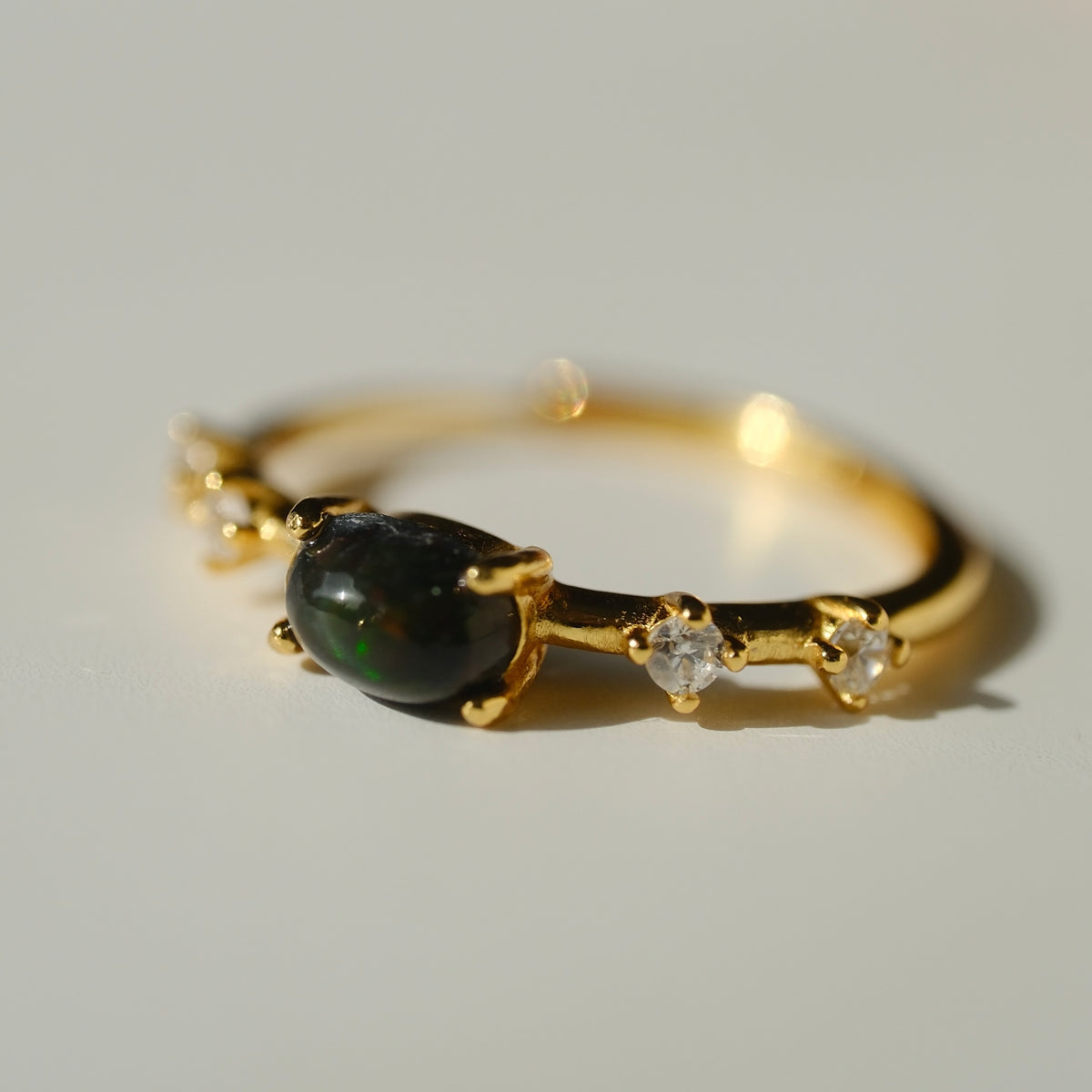 Ethiopian Black Opal adjustable ring with a gold-coloured band and clear accents