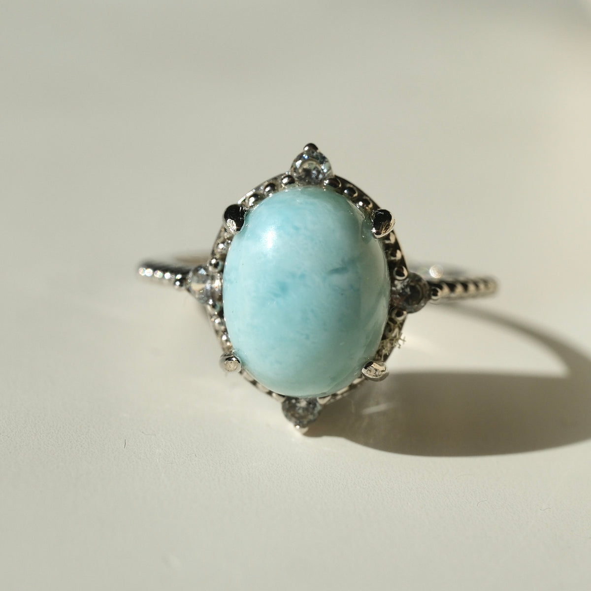 Larimar S925 adjustable ring with an oval pale blue stone, decorative silver border and clear accents