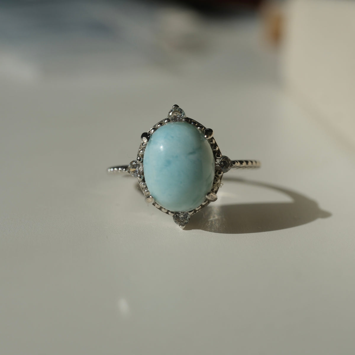 Larimar S925 adjustable ring with an oval pale blue stone, decorative silver border and clear accents