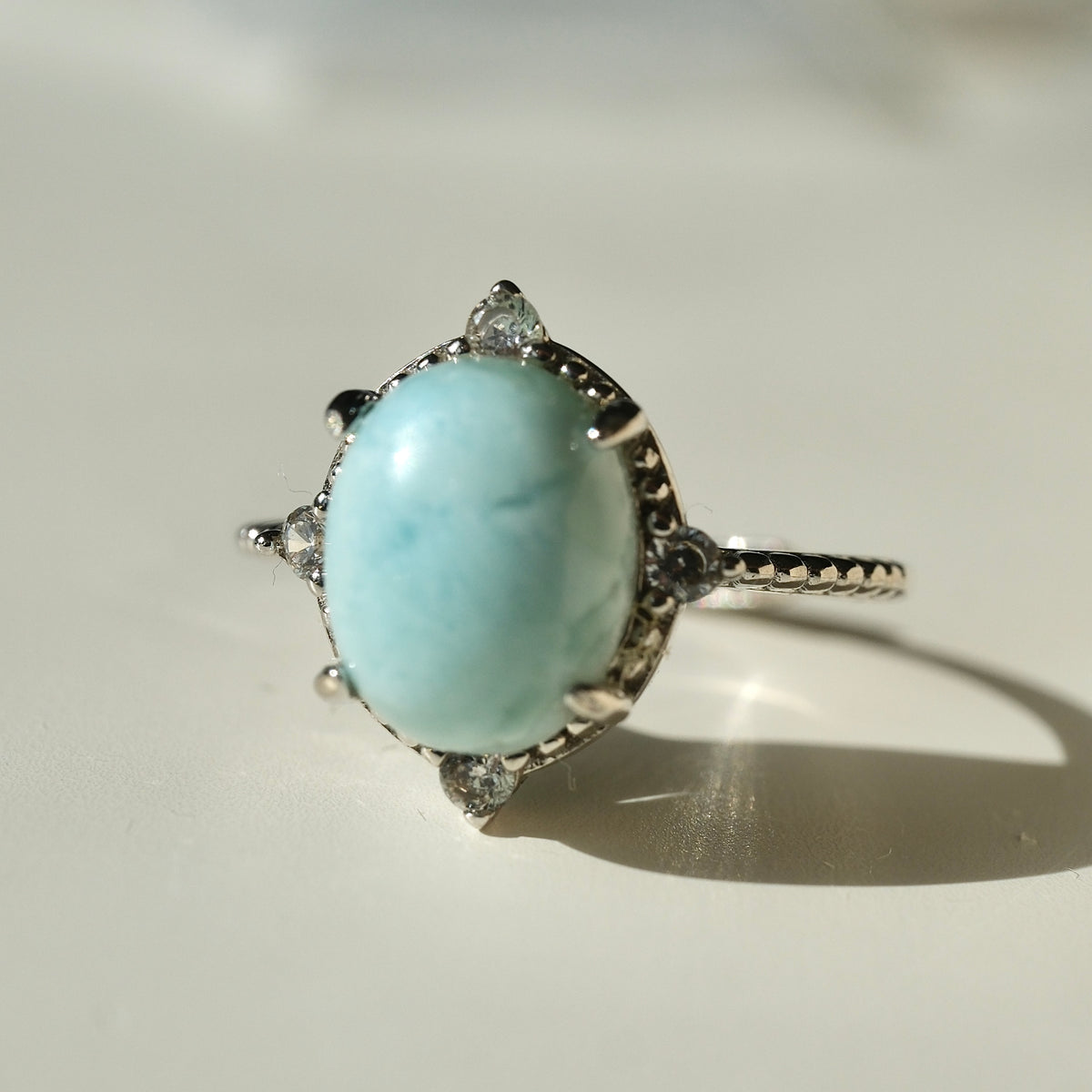 Larimar S925 adjustable ring with an oval pale blue stone, decorative silver border and clear accents