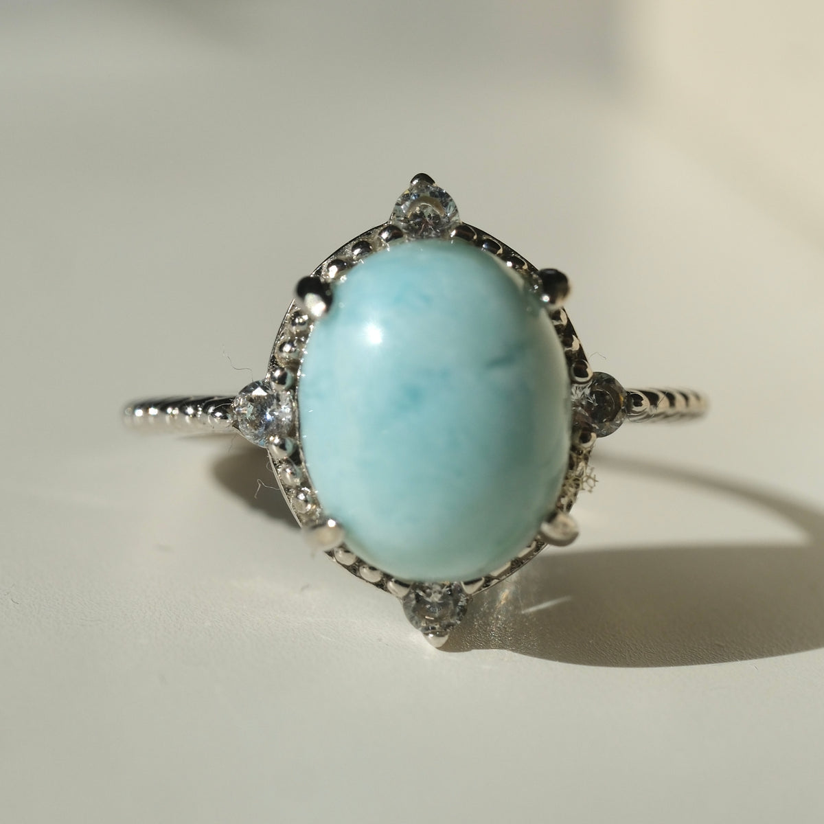 Larimar S925 adjustable ring with an oval pale blue stone, decorative silver border and clear accents