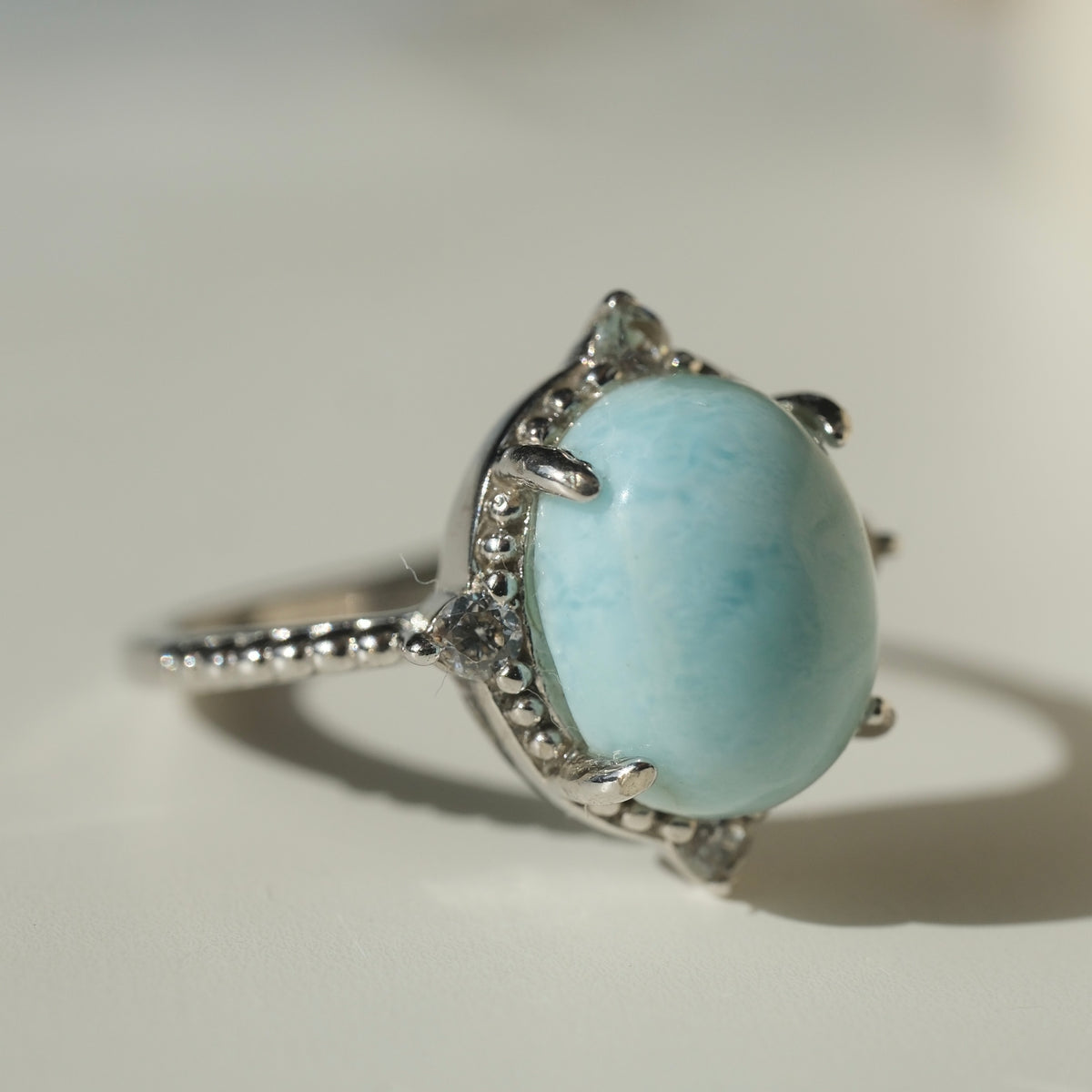 Larimar S925 adjustable ring with an oval pale blue stone, decorative silver border and clear accents
