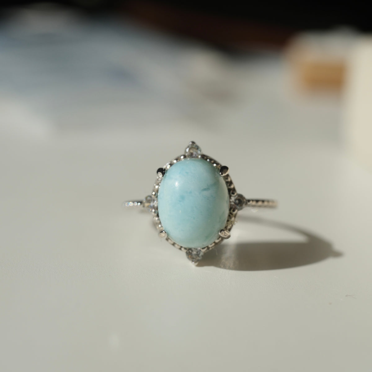 Larimar S925 adjustable ring with an oval pale blue stone, decorative silver border and clear accents