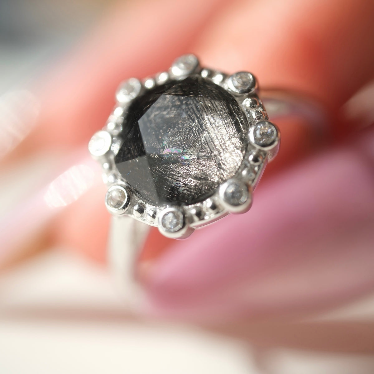 Muonionalusta ring showing the reflective faceted centre and clear halo accents