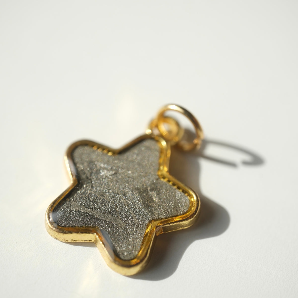 Muonionalusta meteorite star necklace pendant in a gold-tone setting, front view