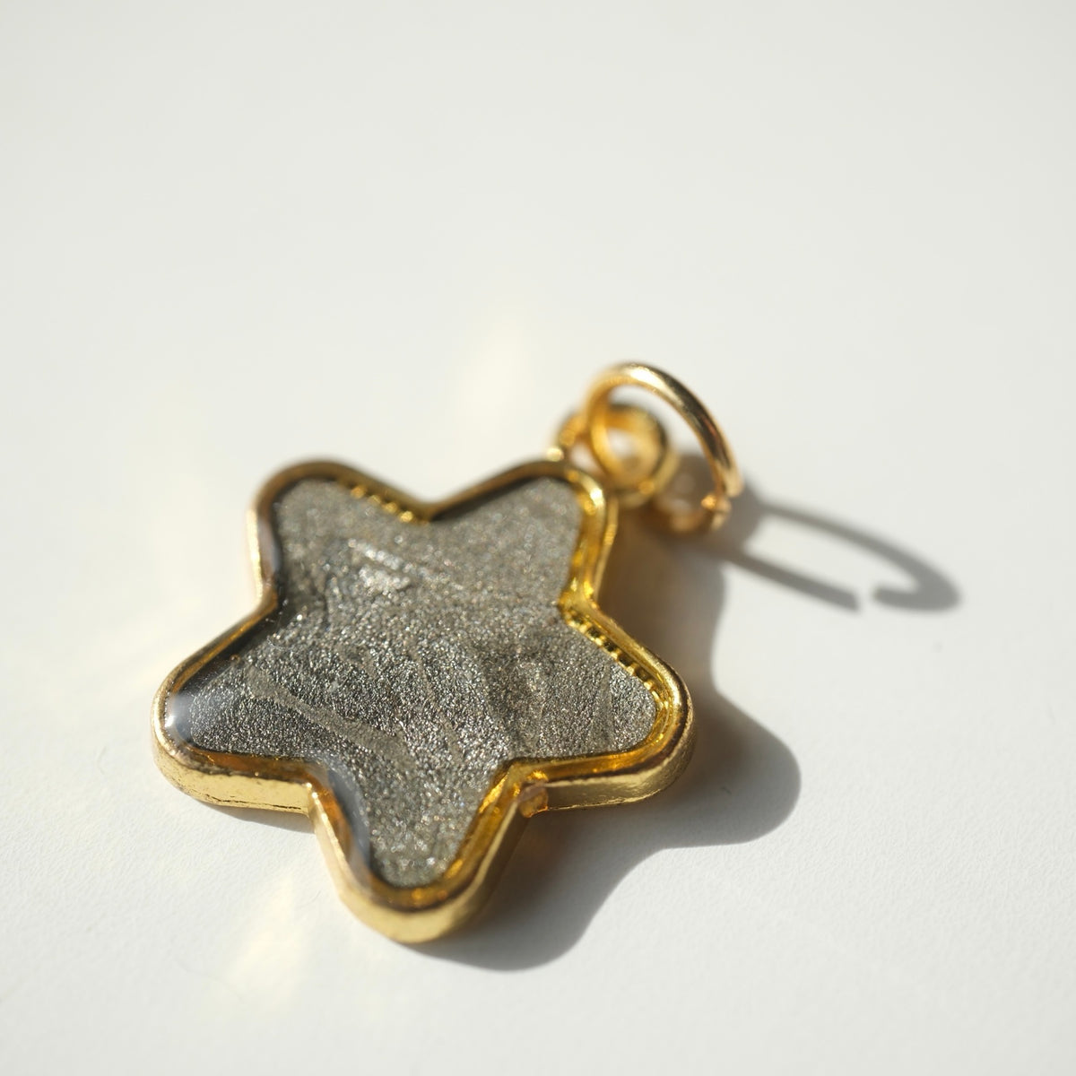 Angled view of the Muonionalusta star pendant and gold-tone bail