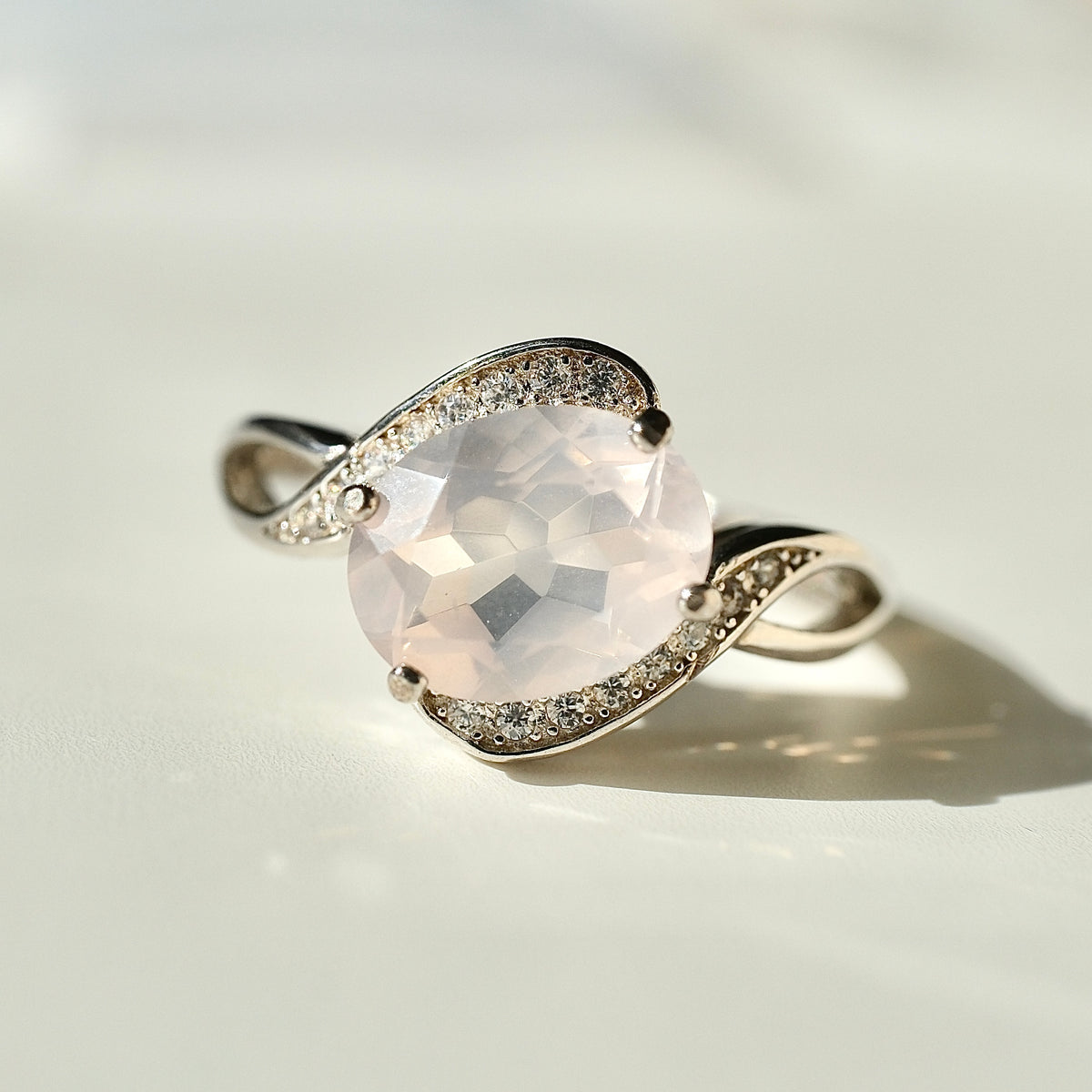 Rose Quartz S925 adjustable ring with a faceted pale pink centre stone and sweeping silver shoulders set with clear accents