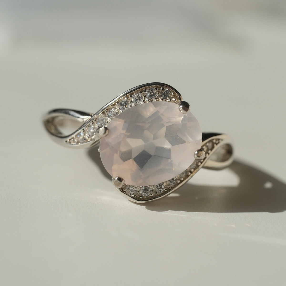 Rose Quartz S925 adjustable ring with a faceted pale pink centre stone and sweeping silver shoulders set with clear accents