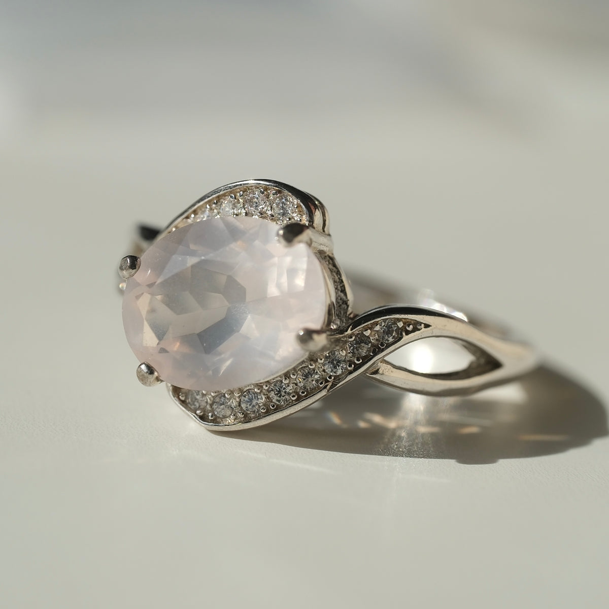 Rose Quartz S925 adjustable ring with a faceted pale pink centre stone and sweeping silver shoulders set with clear accents