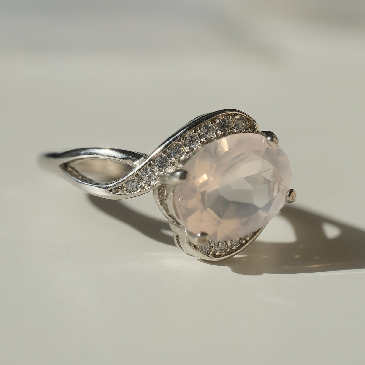 Rose Quartz S925 adjustable ring with a faceted pale pink centre stone and sweeping silver shoulders set with clear accents