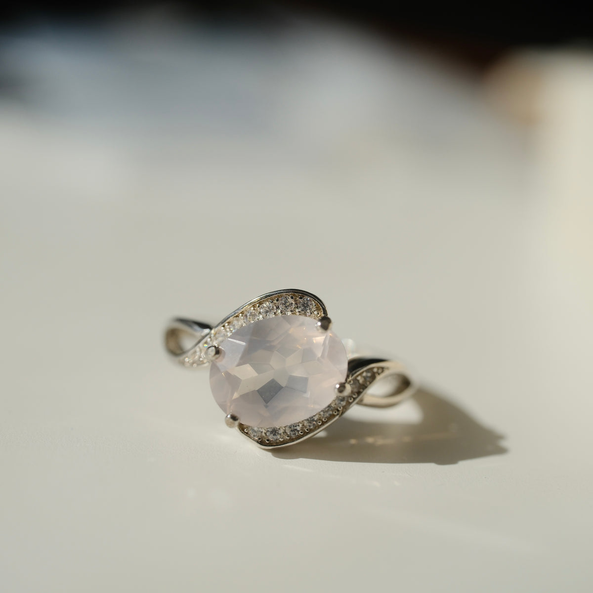 Rose Quartz S925 adjustable ring with a faceted pale pink centre stone and sweeping silver shoulders set with clear accents