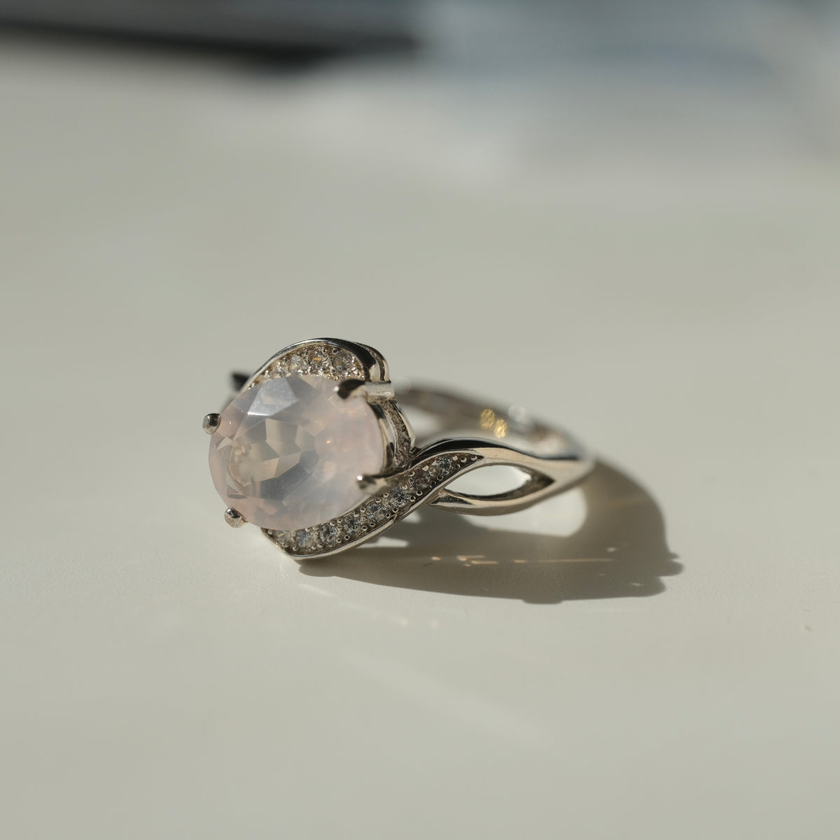 Rose Quartz S925 adjustable ring with a faceted pale pink centre stone and sweeping silver shoulders set with clear accents