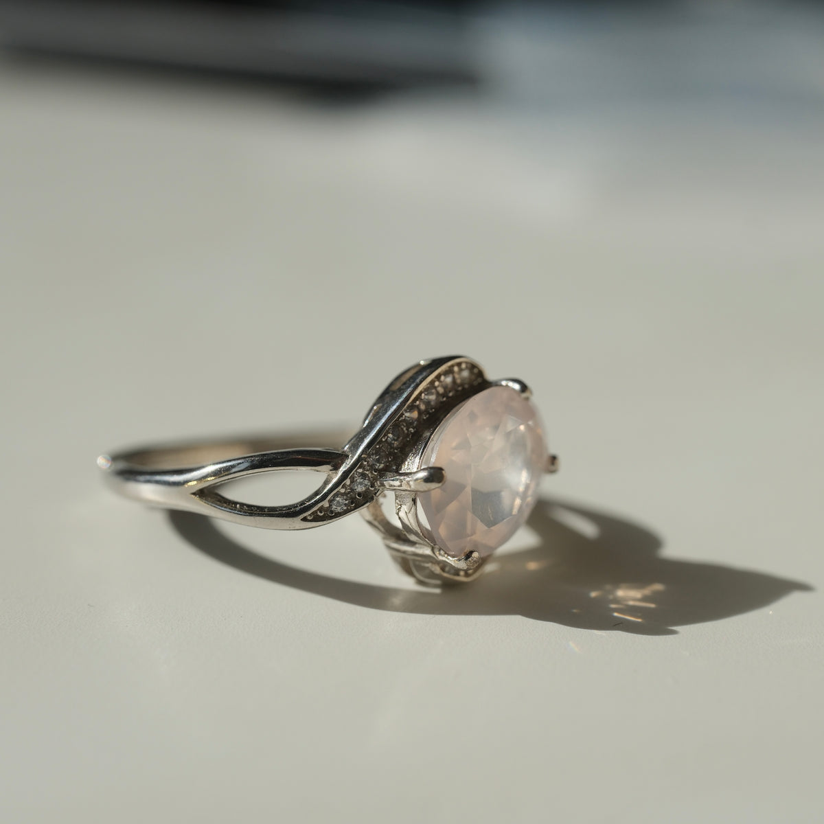 Rose Quartz S925 adjustable ring with a faceted pale pink centre stone and sweeping silver shoulders set with clear accents